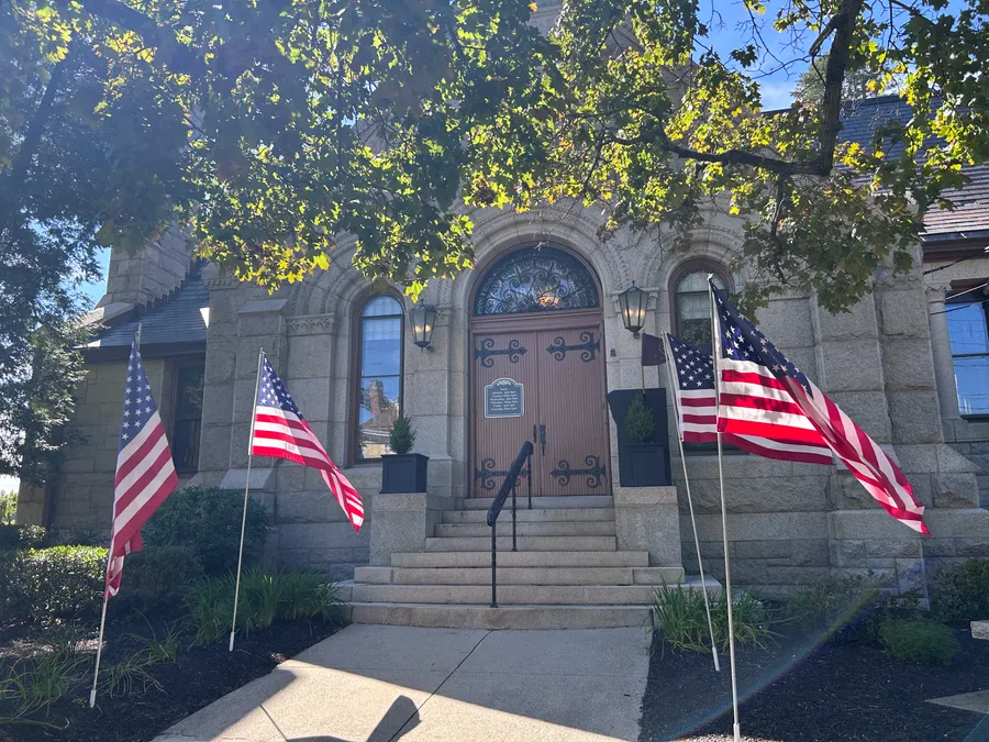Bancroft Memorial Library entrance with American flags in Hopedale, MA.