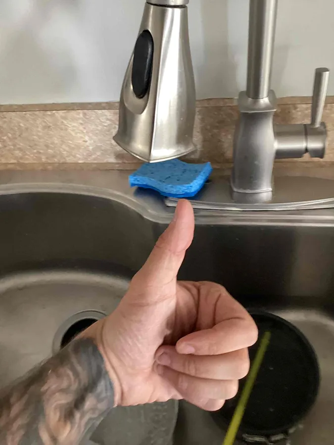 Technician giving thumbs up after drain cleaning in kitchen sink in Franklin, MA.