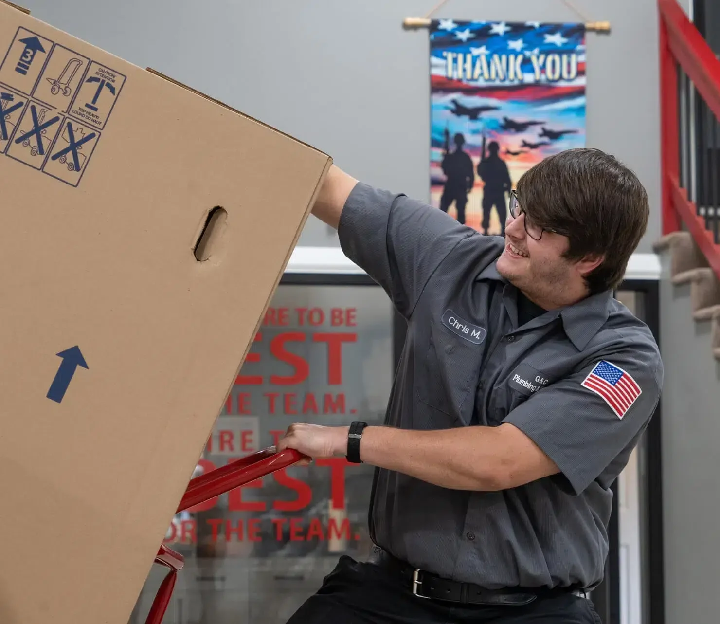 Technician loading water heater into truck in G&C Plumbing and Heating warehouse in Franklin, MA.