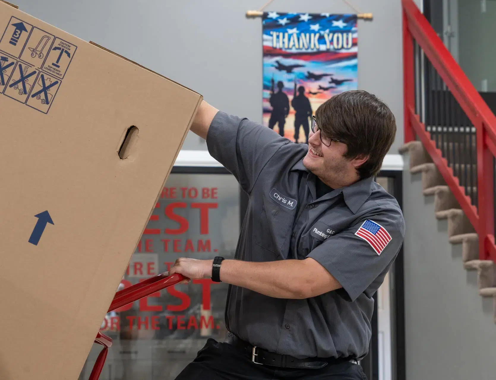 Technician loading water heater into truck in G&C Plumbing and Heating warehouse in Franklin, MA.